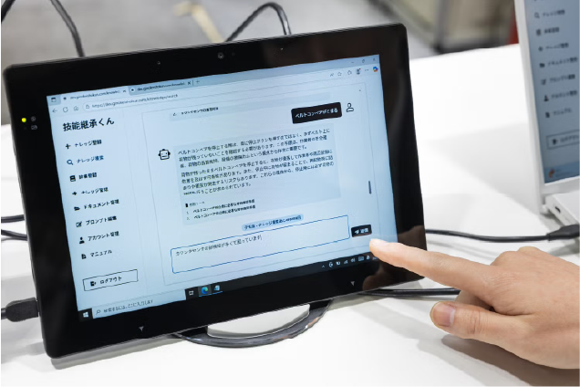 タブレット端末に表示された「技能継承くん」のチャット画面を指で操作する様子