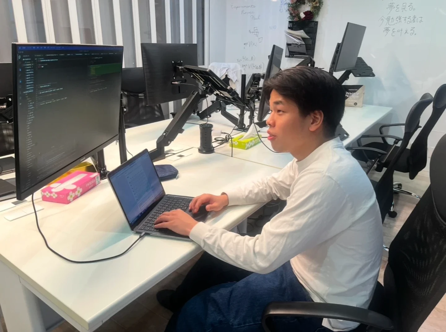 モニターとノートPCを並べたオフィスのデスクで開発作業をする様子
