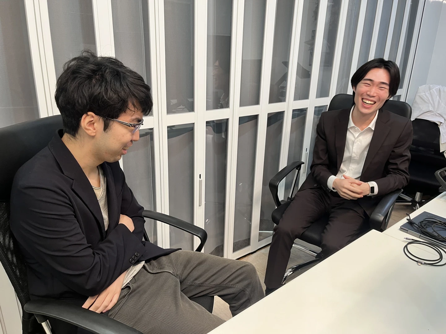 インタビュー中、椅子に座って談笑する小安（右）